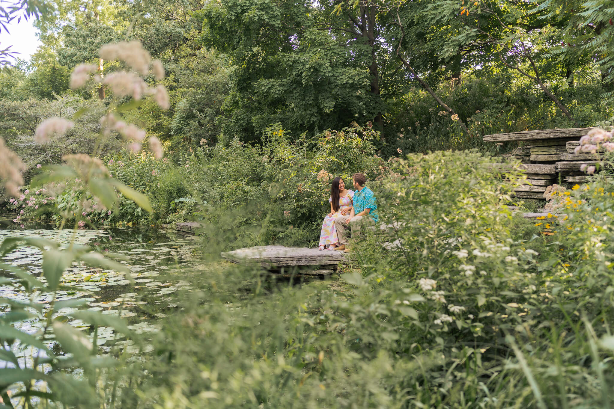 A couple sits on a bench, nestled in the greenery at the Lily Pool.
