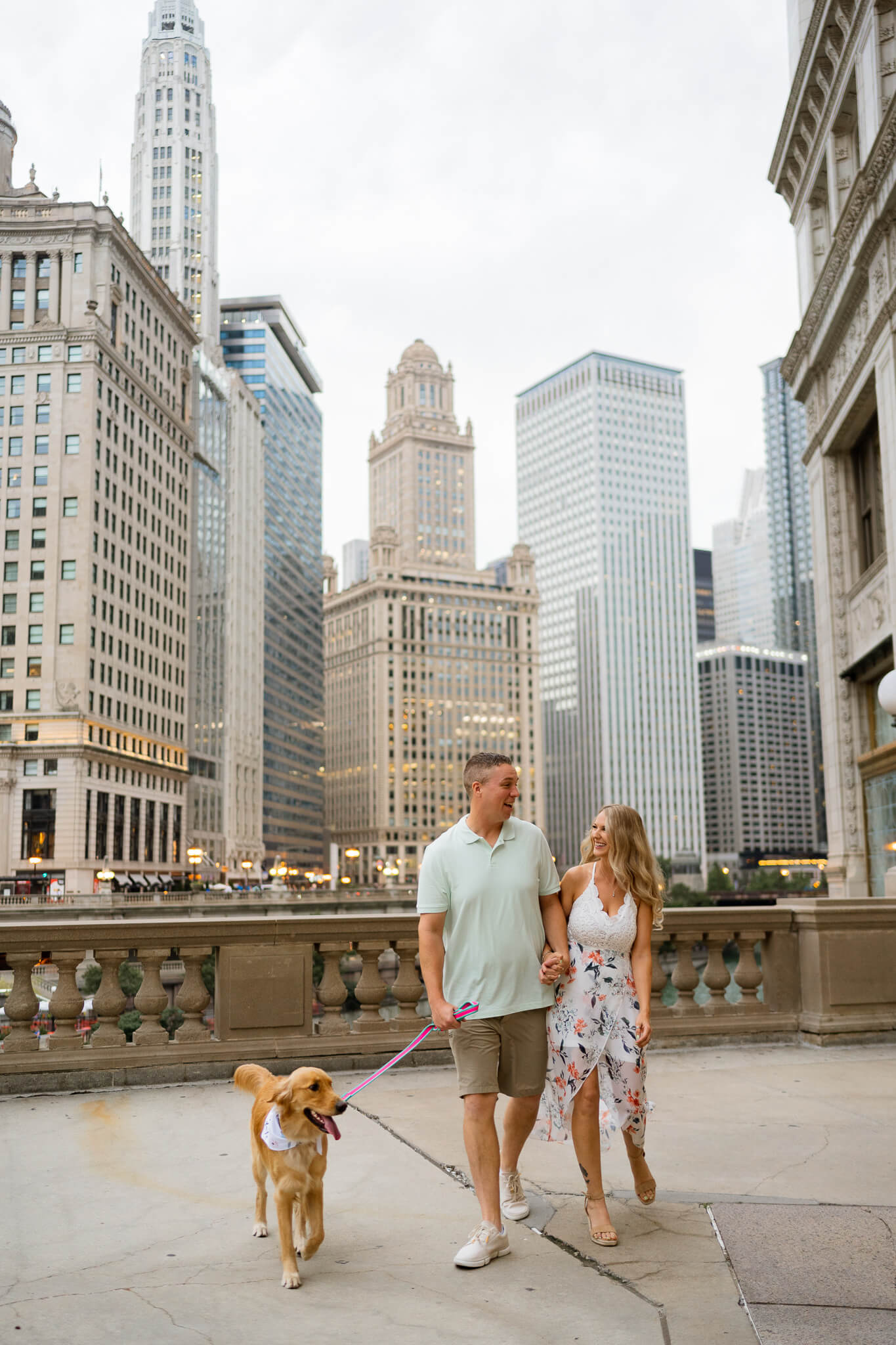 A couple bumps hips while walking with their dog at Chicago's Wrigley Building