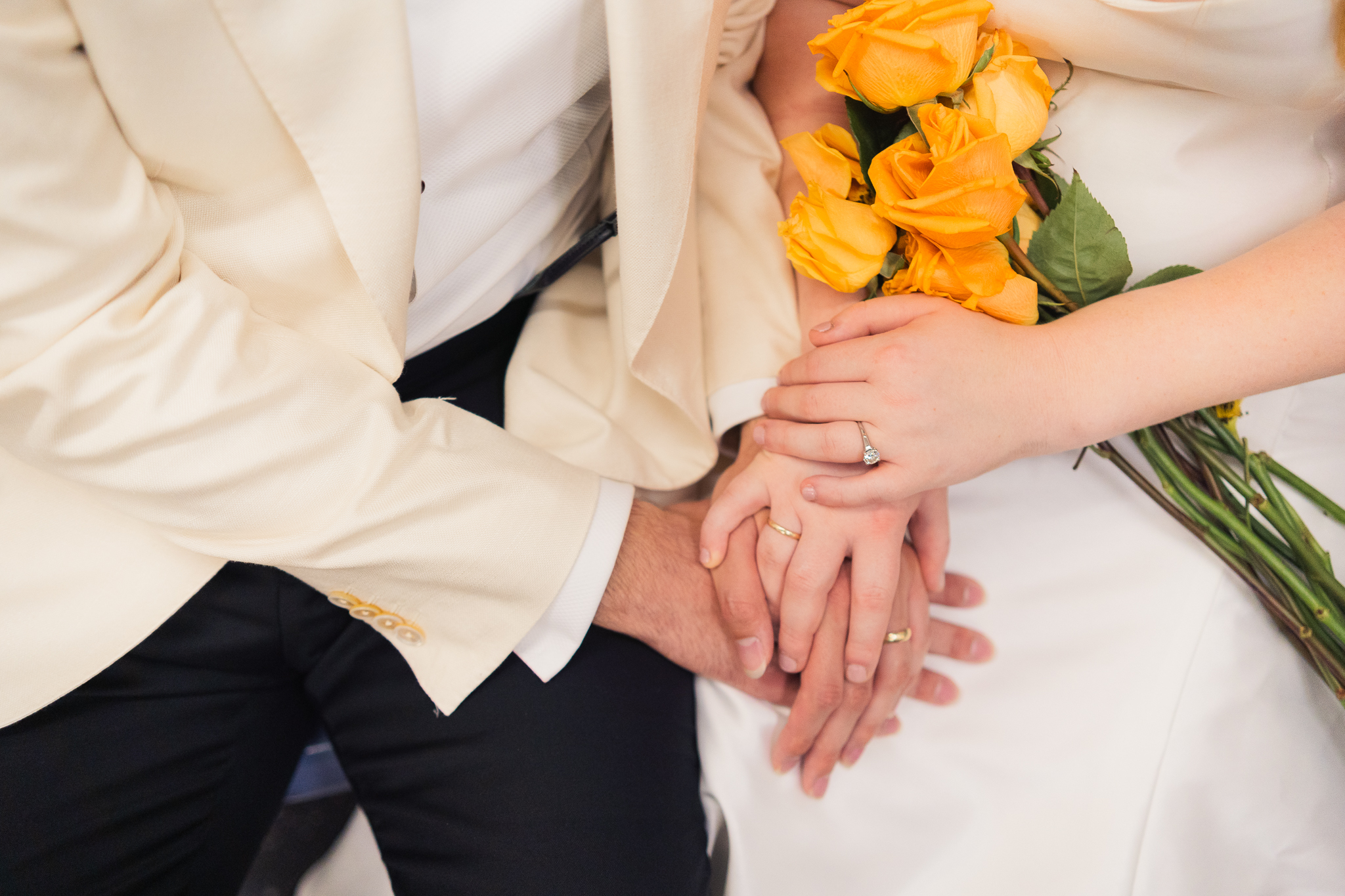 bride and groom holding hands with a bouquet of yellow flowers