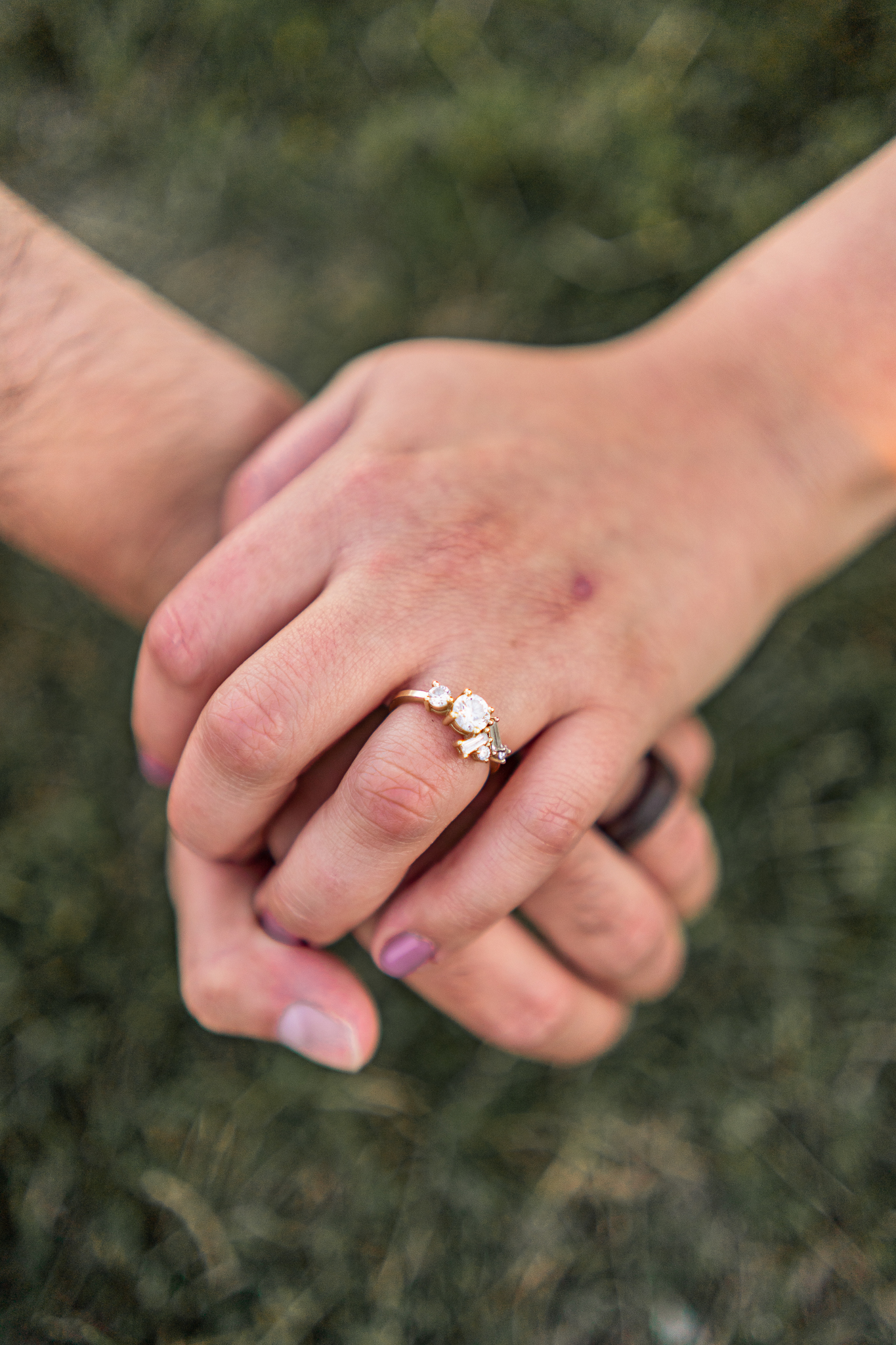 details of an engagement ring while holding hands