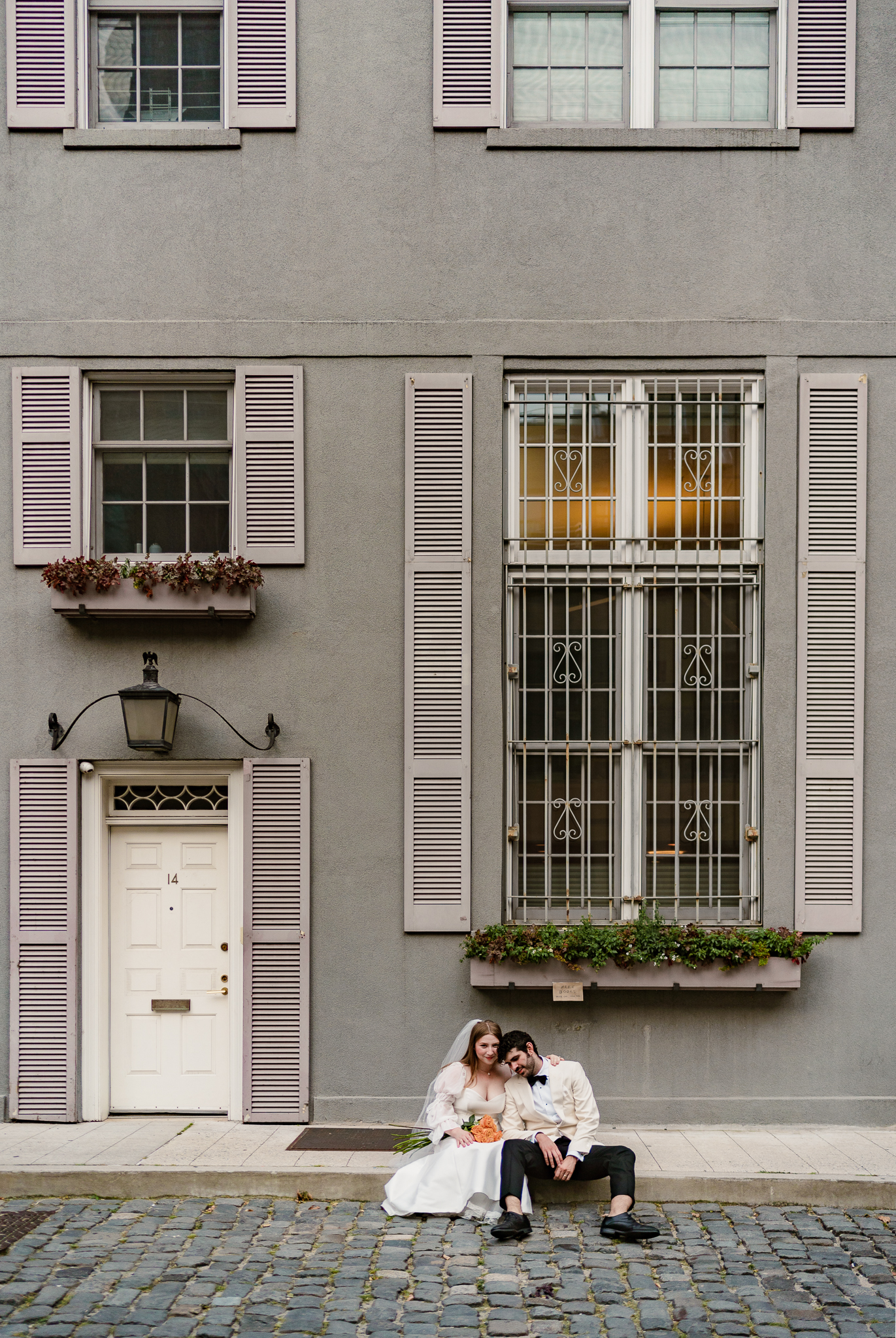 bride and groom sitting on the sidewalk in front of a house at their chicago wedding