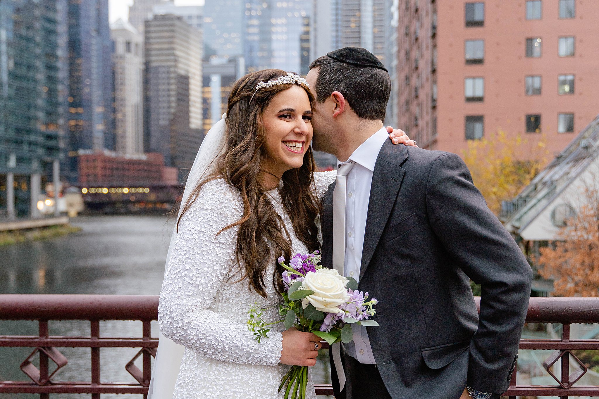 groom whispering in his bride's ear in front of the Chicago skyline taken by a Jewish Wedding Photographer