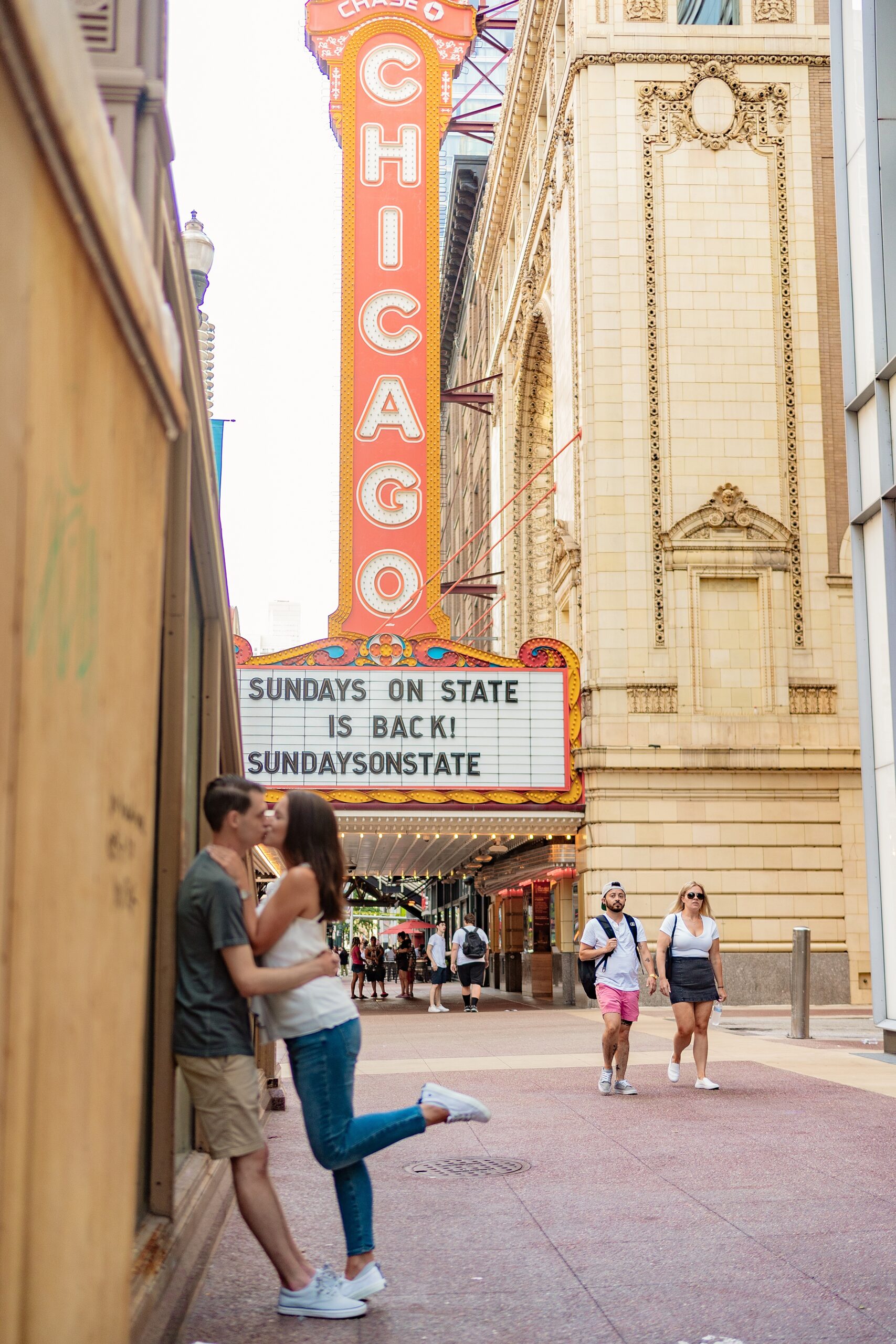 couple sharing a kiss outside of the Chicago theatre chicago engagement photos