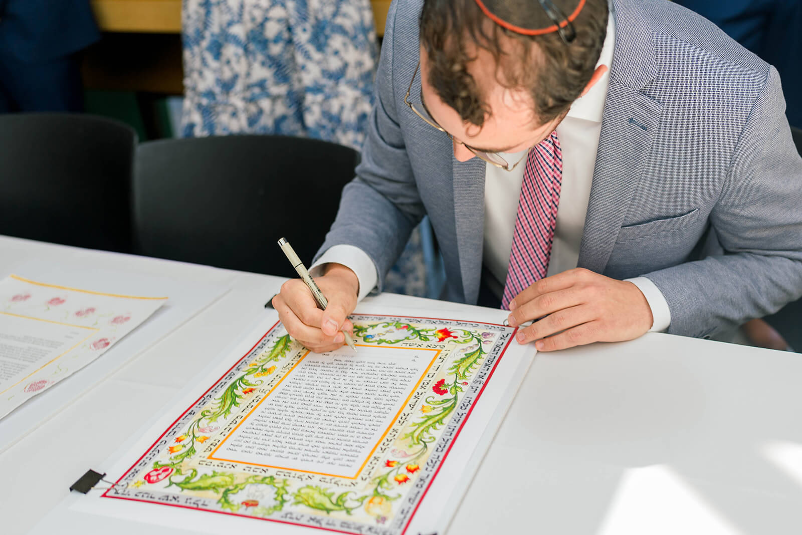 Closeup of a Jewish man signing the Ketubah as a witness at a wedding