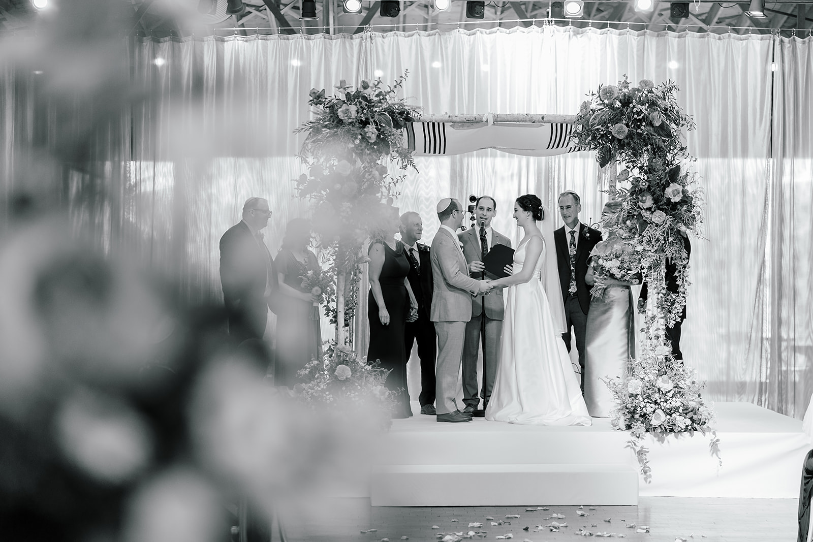 A bride and groom hold hands under the arbor at the altar during their Jewish wedding ceremony
