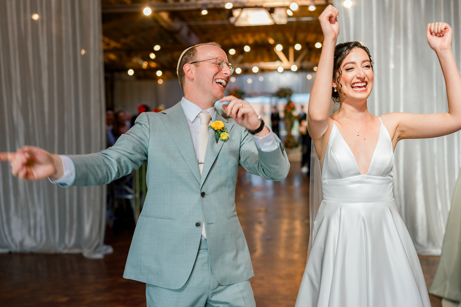 Newlyweds dance and cheer as they enter their Jewish wedding reception in style
