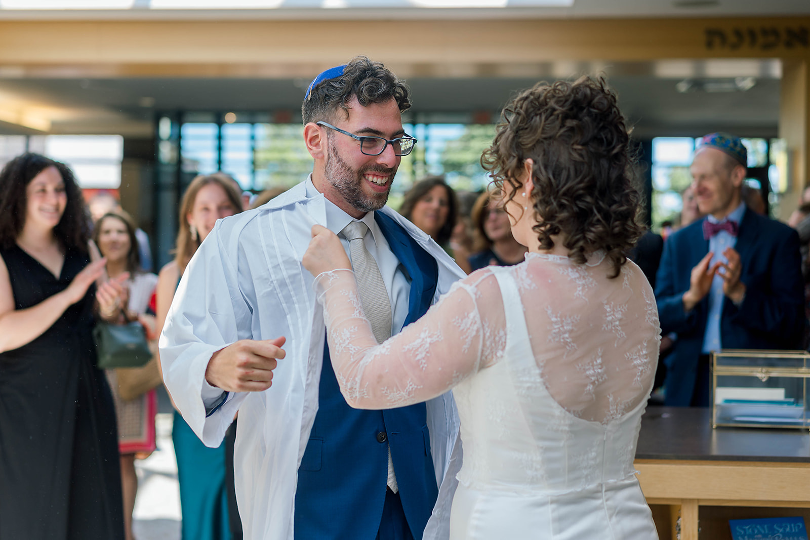 A bride helps her groom put on his white robe during their ceremony